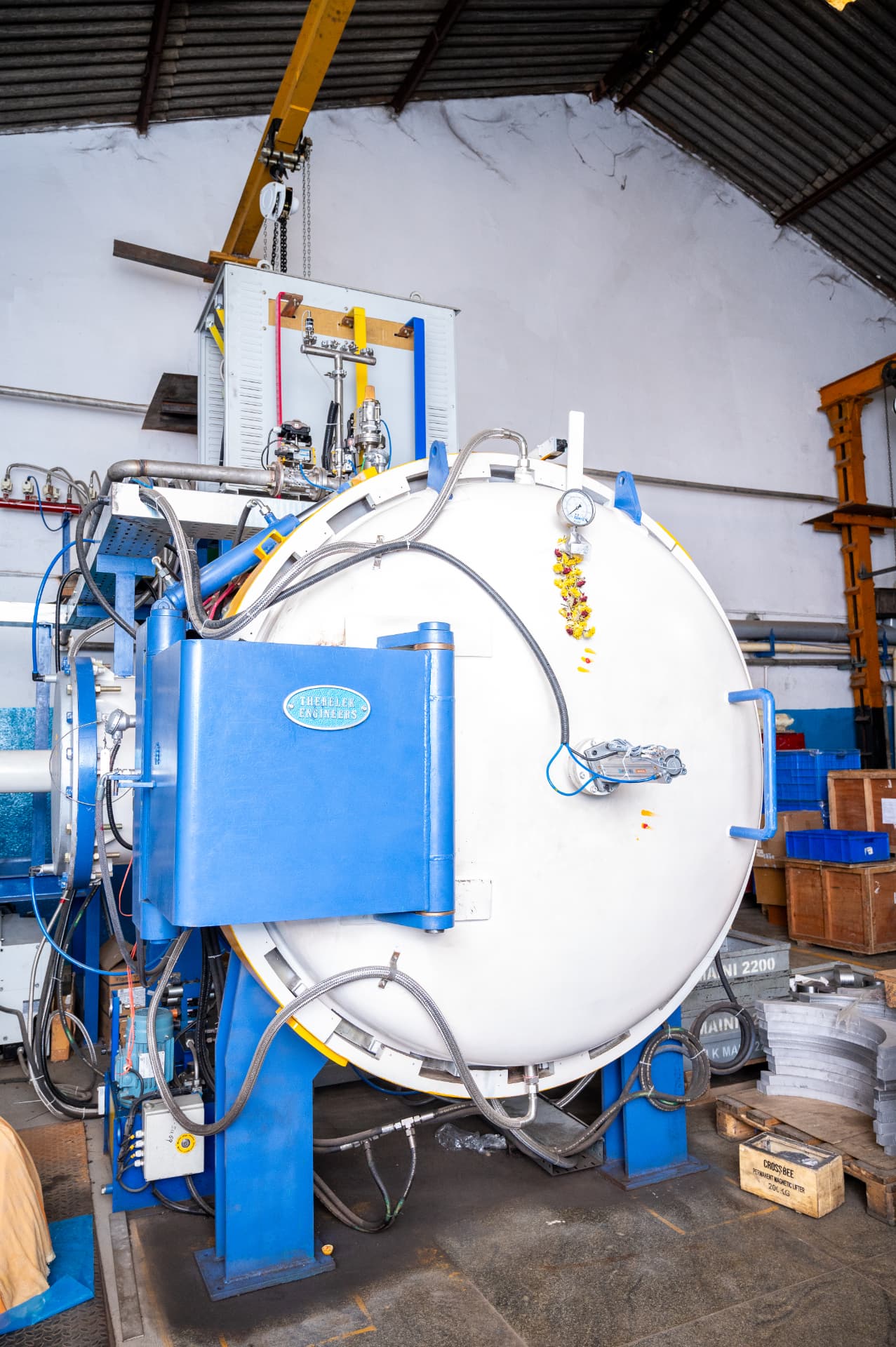 Horizontal vacuum furnace vessel with instrumentation and hoses inside a manufacturing bay